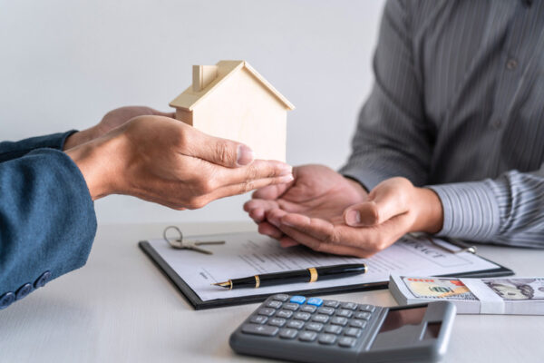 Real estate agent are presenting home loan and giving house to customer after signing contract to buy house with approved property application form.